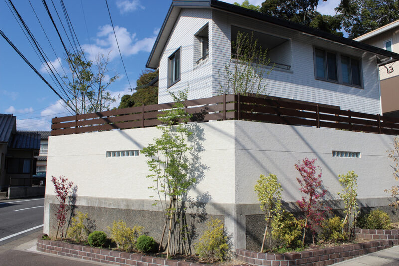 外からの塀の高さ、ガラスブロック・木調板塀のバランス、植栽の高さも考慮しています。