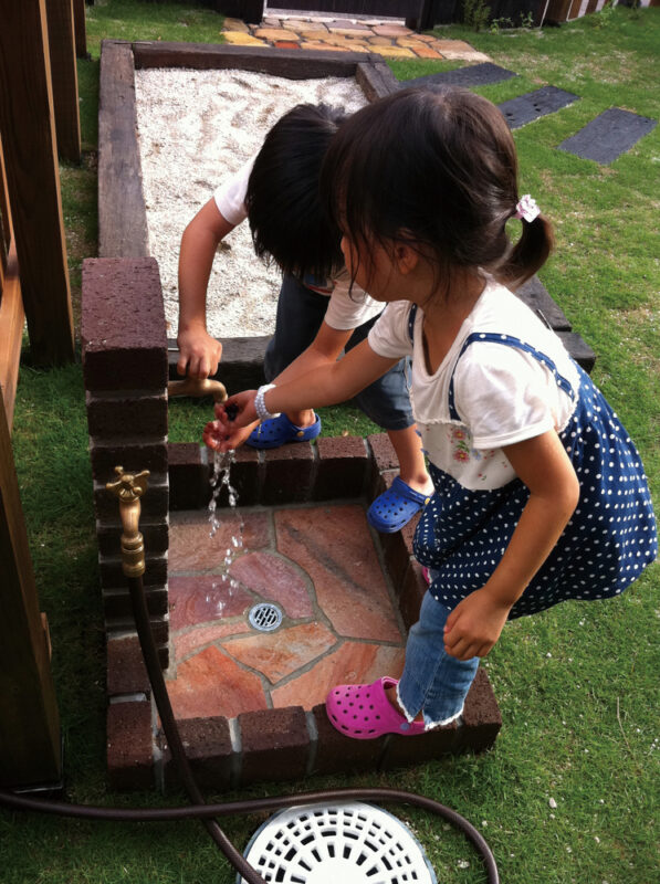 レンガでつくった立水栓で子供達がブルーベリーを洗ってます。