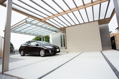 玄関前のカーポートは、高級感漂うLIXILの＋G。フリーウォールと内天井を設けることで、アプローチと駐車スペースを仕切りました。