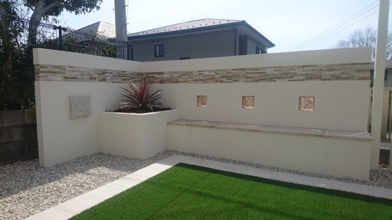 淡い色でまとめたオリジナルの塀には 植栽スペースとベンチを設置
