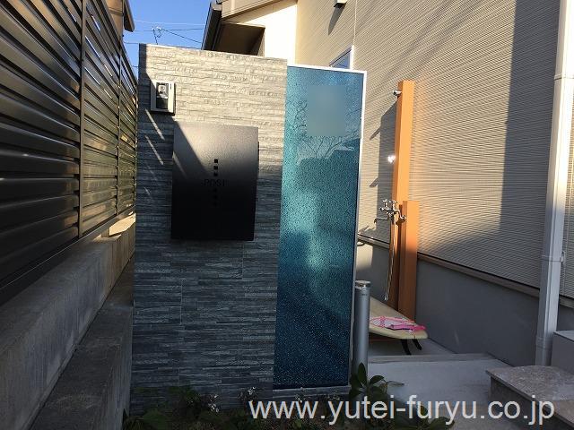 ブラックの自然石貼りと対照的なブルーのティンクルで、カッコいい門袖を。玄関わきにはサーフィン後に使用できるシャワーも設けました。陽があたると、一段と輝いて見えます。