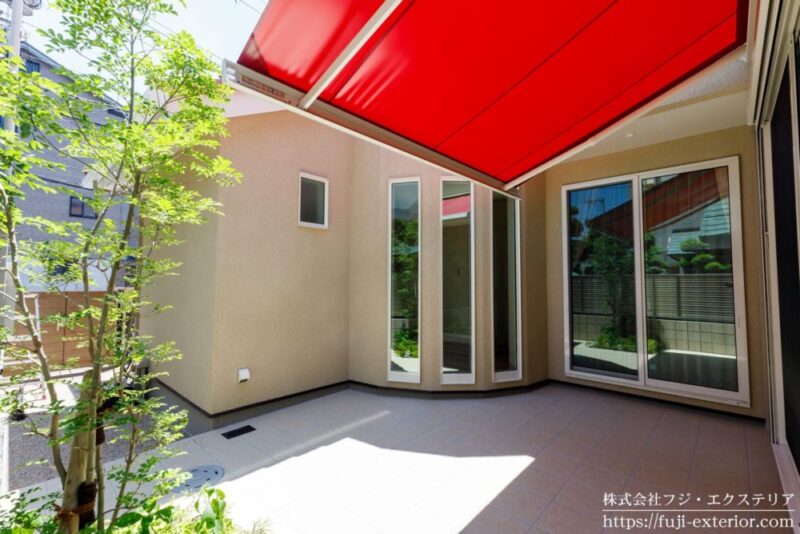 キュートな赤の大型オーニングテントが、テラスに日陰を作ってくれる
