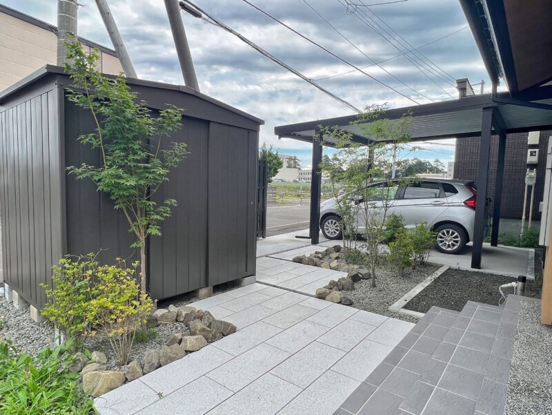 和モダンは植栽と足元が重要です
こちらの和モダンのデザインは、アプローチのインターロッキングの素材選びから始まります。
表面にショットブラストを施したインターロッキングにすることで、本物の御影石のようなテイストが再現できています。
アプローチの動線としては、クランクにすることで樹木を植える場所が確保でき空間に余裕を持たせることができるのと、和風庭園のような飛石風のアプローチを和モダンテイストで表現することができます。